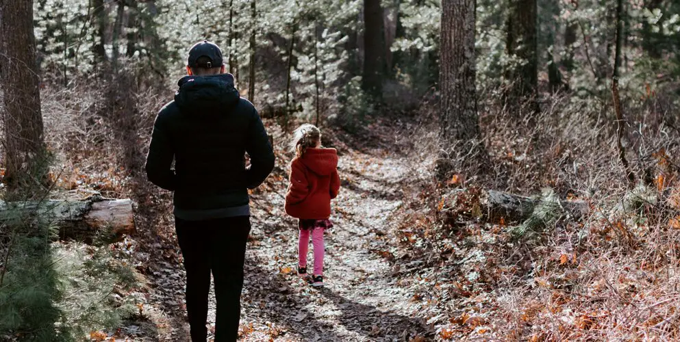 father walking in the woods with child