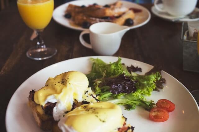 Florentine Benedict, salad, and tomatoes on a plate with orange juice and toast