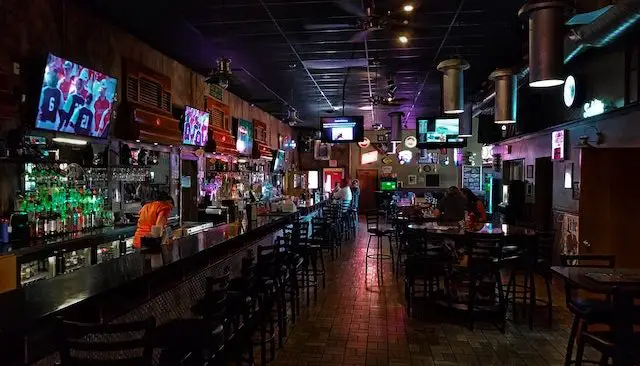 a long bar counter with chairs and a few people sitting down 