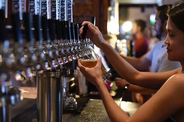 woman filling up a glass of beer from a tap