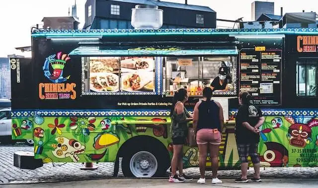 food truck with 3 customers standing in front ordering food