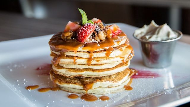 stack of pancakes with strawberries, nuts, and caramel on top