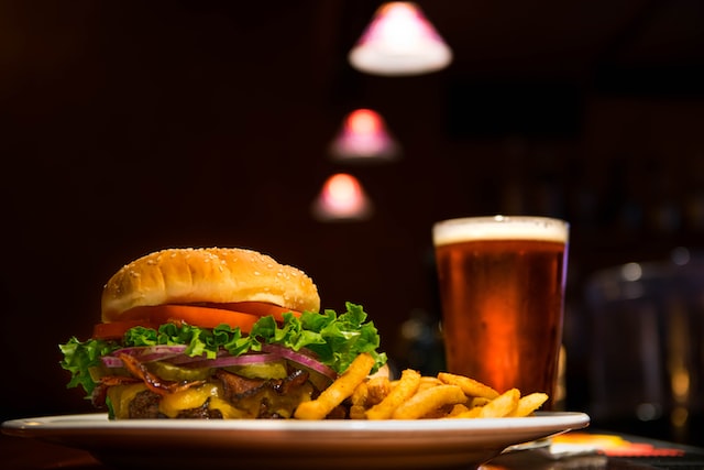 glass of beer, a burger and fries sitting on a table