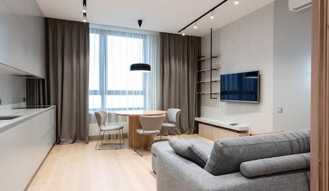 hotel room with couch, table, chairs, and television hanging on the wall