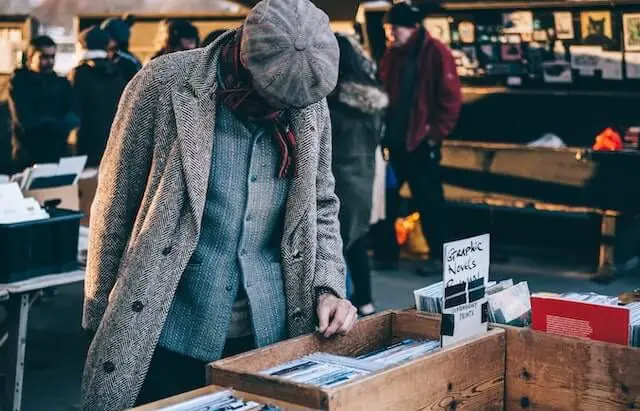 man searching through box of goods at a flea market