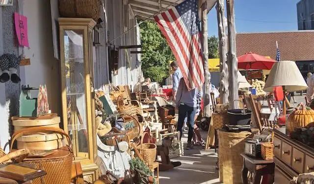 row of flea market goods outside on the sidewalk with an America flag hanging down