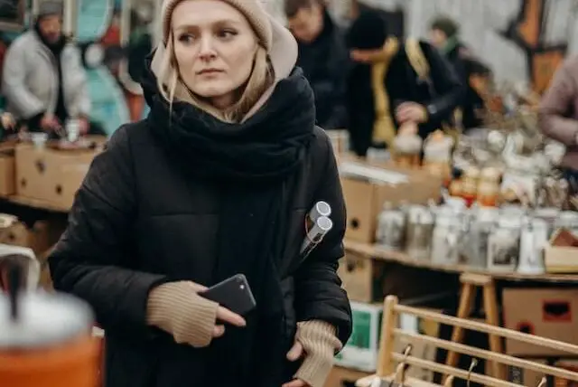 woman in a black coat shopping at a flea market