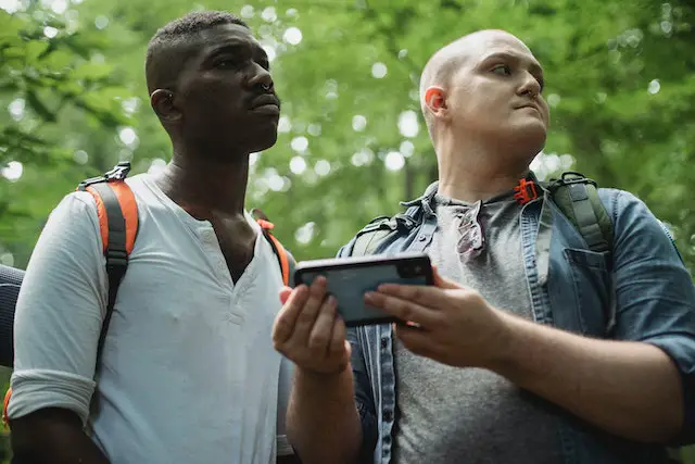 2 men using their phone in the woods