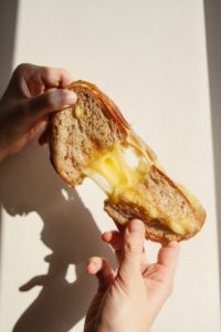 grilled cheese sandwich being pulled apart by 2 hands with the cheese melted inbetween