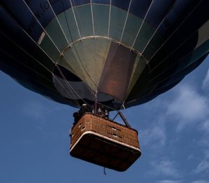 people riding in a hot air balloon, view from underneath the basket looking up