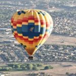 hot air balloon flying over a city