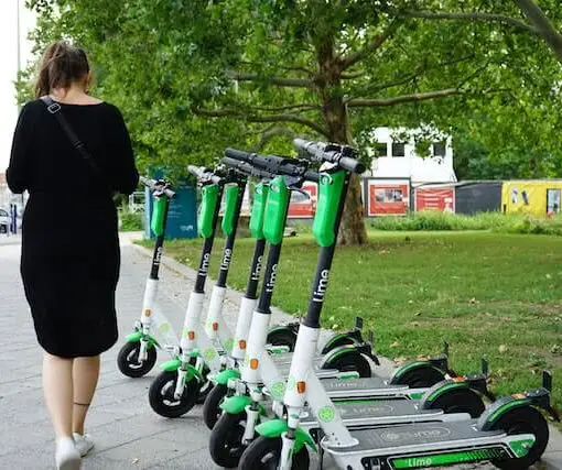 row of lime scooters with female in black dress walking beside them