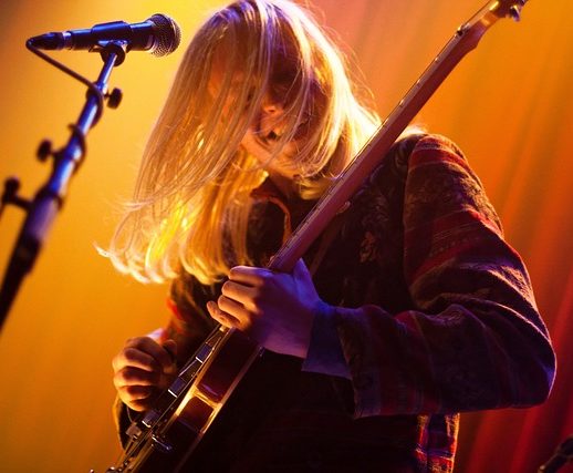 music playing the guitar standing on stage