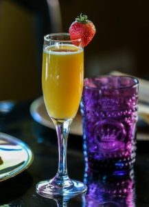 mimosa with a strawberry and purple glass beside it