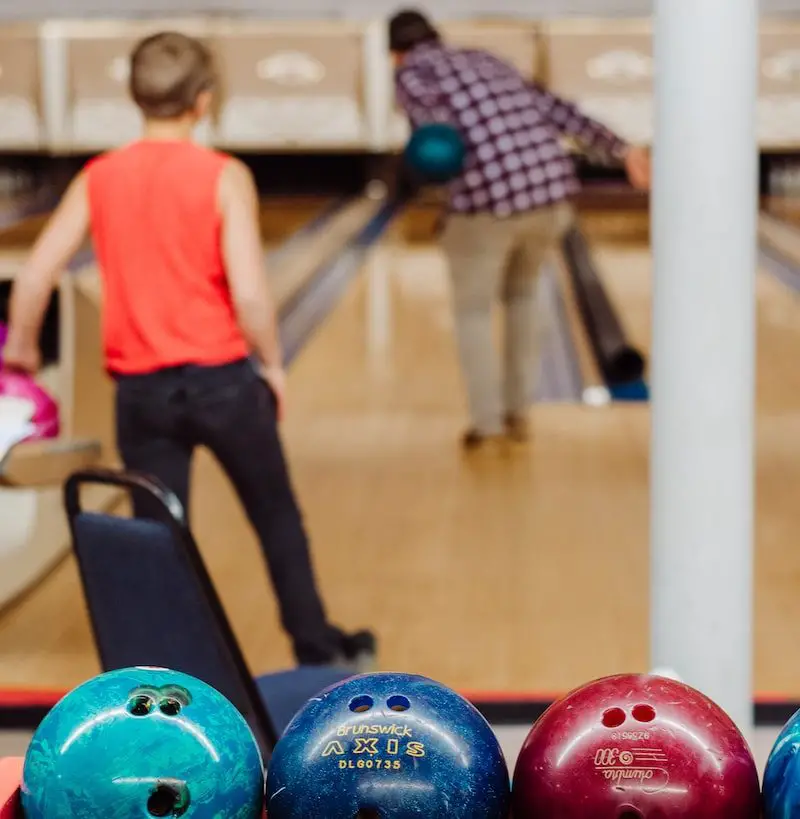 boy in orange t-shirt and black pants standing on blue and black exercise ball