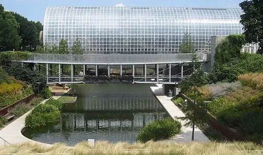 large round glass greenhouse with pond in foreground