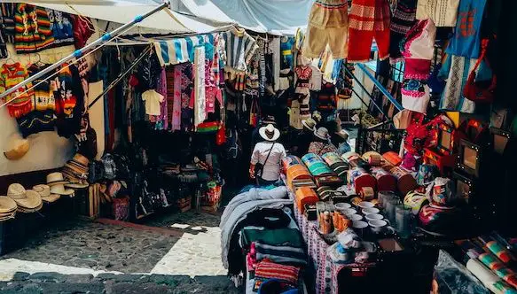 flea market goods with clothing, man in hat standing looking at merchandise