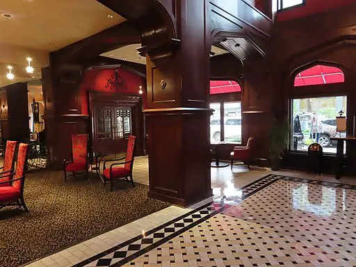 lobby of the Skirvin Hilton Hotel with red chairs, wooden pillars, and black and white tiled floor