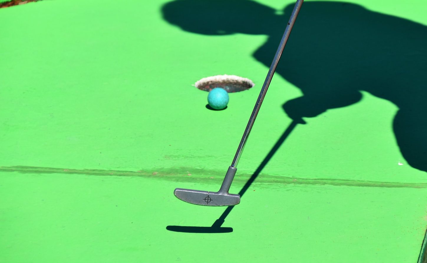 person golfing and ball about to shoot in hole