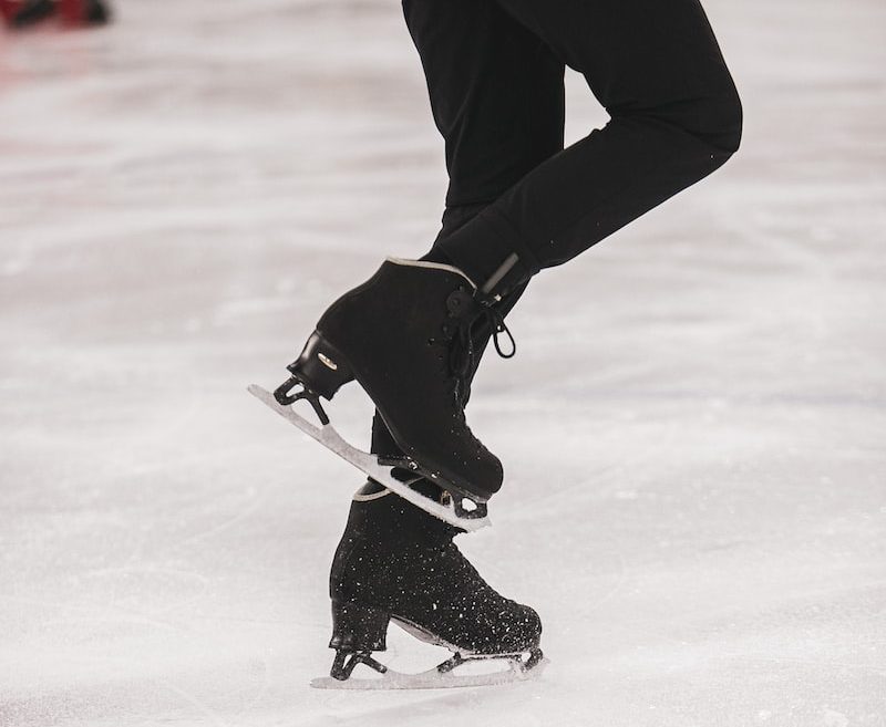 person in black jacket and black pants playing ice hockey