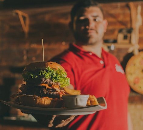 man handing a plate with a hamburger towards the point of view