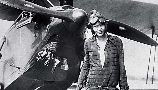amelia earhart standing in front of an airplane