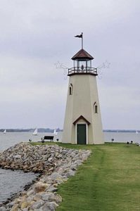 lighthouse by a lake with sailboats in the background