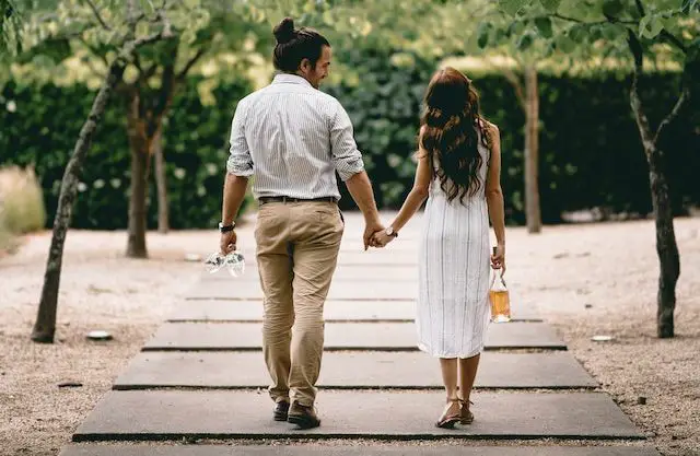 couple holding hands walking on a path