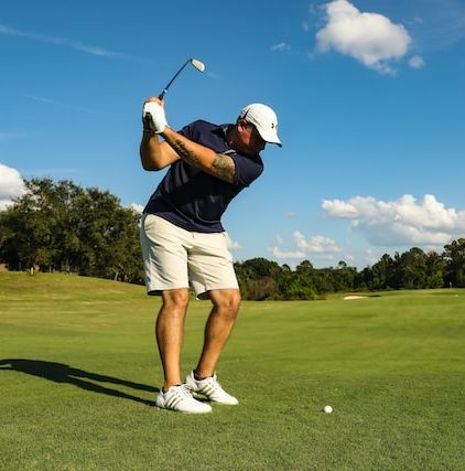 man swinging at golf ball on golf course