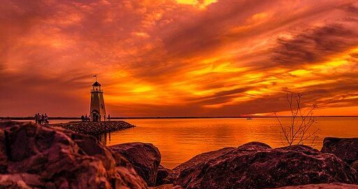 sunset with clouds and a lighthouse with view of lake