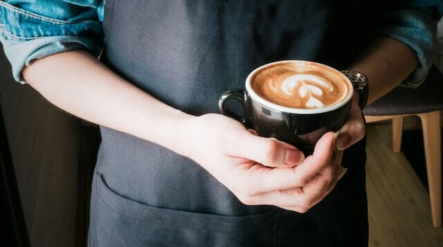 person holding a cup of coffee with latte art