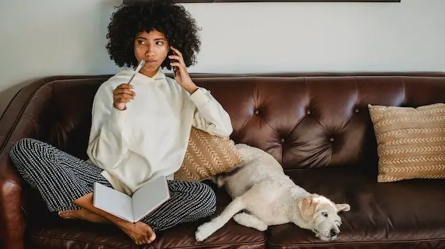 woman on couch with dog thinking about what she is going to write