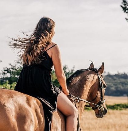 girl riding on the back of a horse in a field