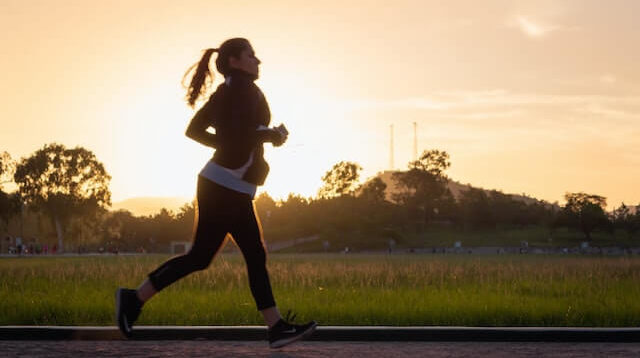 woman jogging with sunset in background