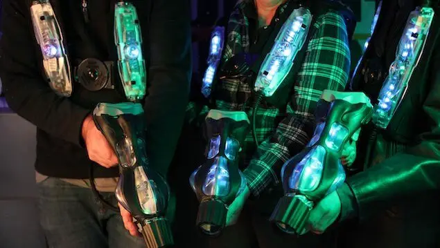 3 people holding laser tag guns and wearing laser tag gear