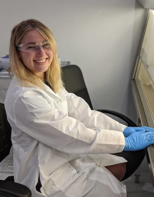 woman sitting in lab coat and latex gloves