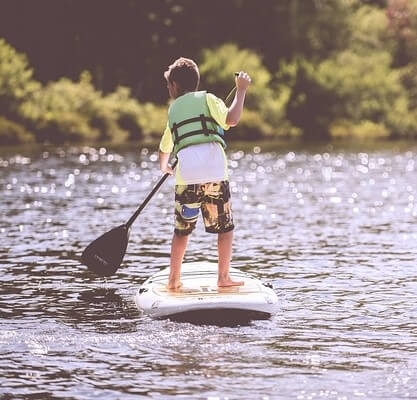 small boy paddleboarding on a lake