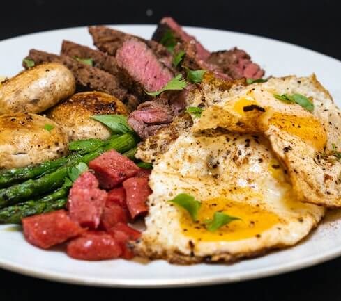 steak, eggs, vegetables on a plate