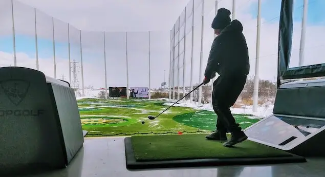 man swinging the club at a golf ball at a topgolf course