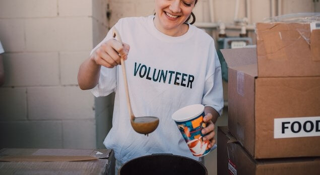 a woman volunteering and pouring soup