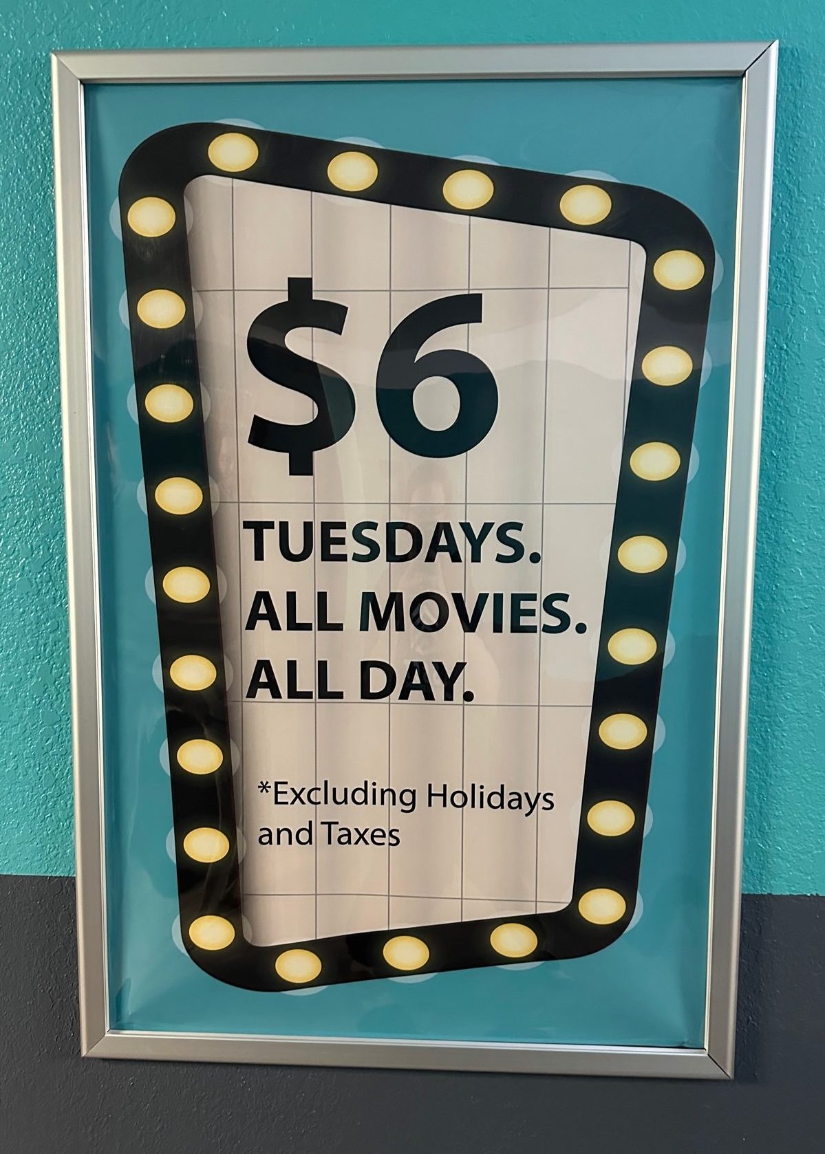 sign that shows price for movies is 6 dollars all day long