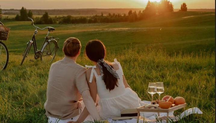 couple having a picnic on the grass at sunset