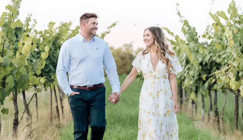 man and woman walking holding hands in a vineyard