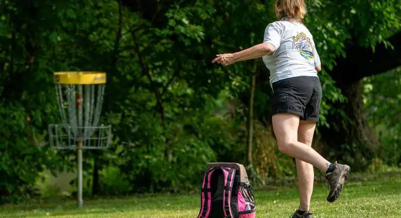 woman throwing a frisbee playing disc golf