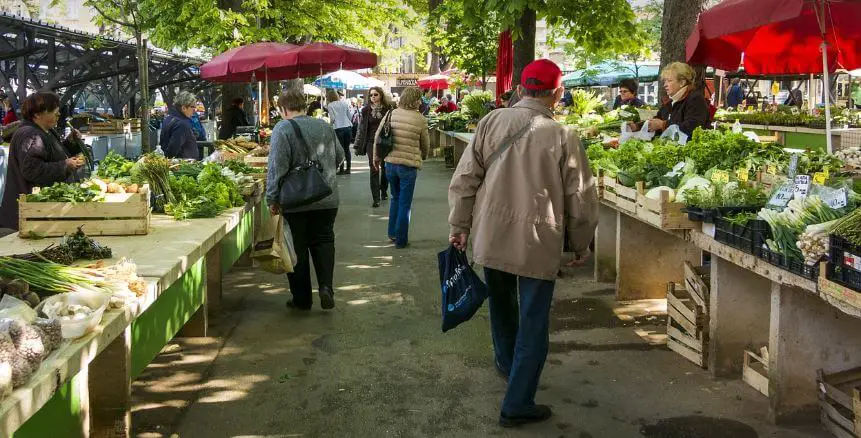 people shopping at a farmers market with produce