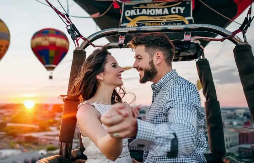 man and woman looking at each other holding hands in hot air balloon