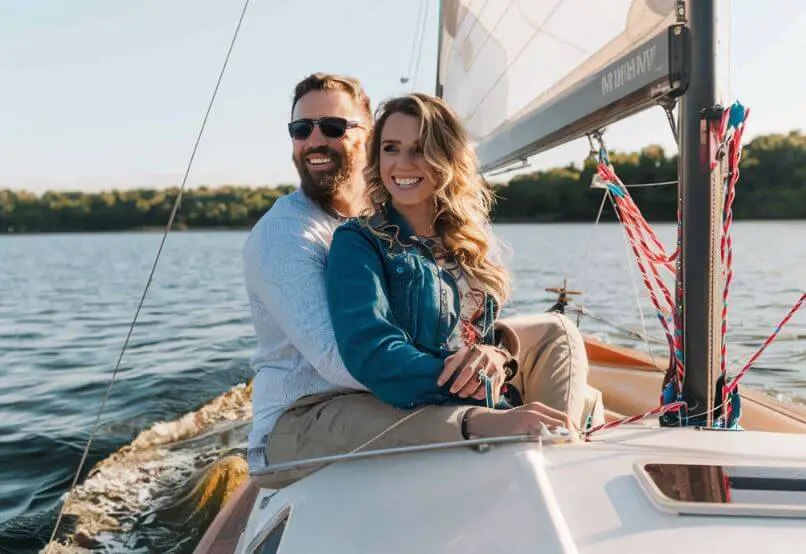 man cuddling woman while riding on a sailboat