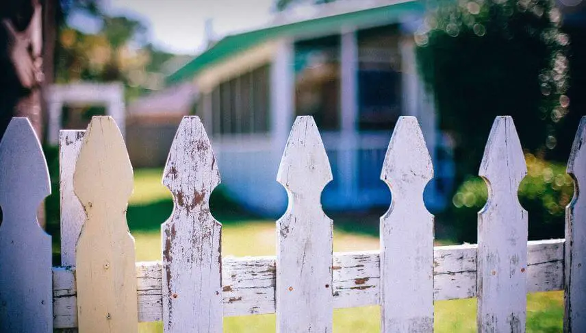 white picket fence with house in the background