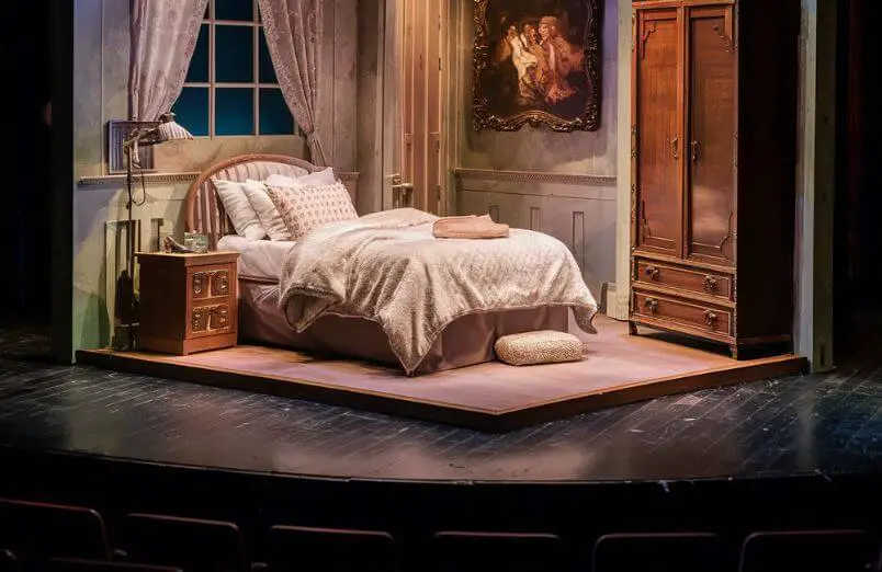 a stage setting with a bedroom setup such as a bed, dresser, etc.
