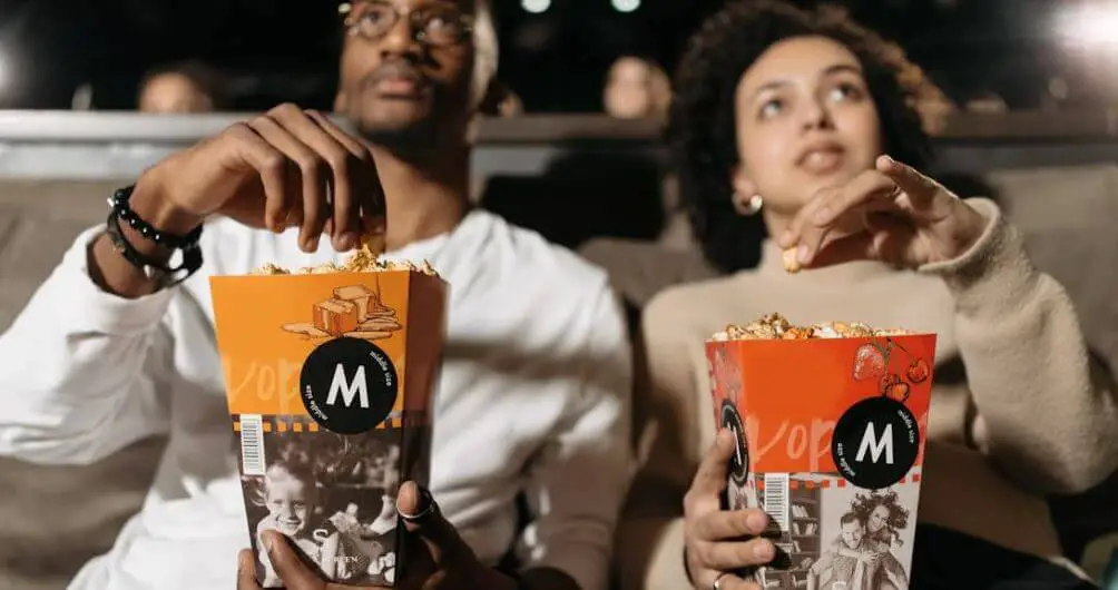 man and woman eating popcorn watching a movie